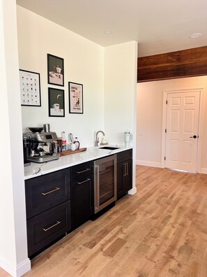 A modern kitchen with a coffee machine, sink, and black cabinets.
