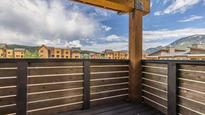 Une terrasse en bois offrant une vue sur une rangée de bâtiments et, au loin, sur des montagnes.