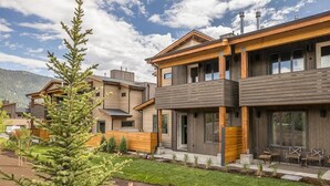 Un immeuble résidentiel moderne avec une façade en bois, de grandes fenêtres et une pelouse bien entretenue.
