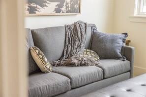 A grey sofa with patterned pillows and a knitted throw.