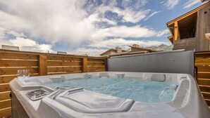 Boblebad med træterrasse og en træhytte i baggrunden.