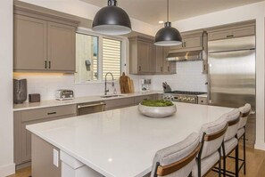 A modern kitchen with a central island, stainless steel appliances, and pendant lighting.