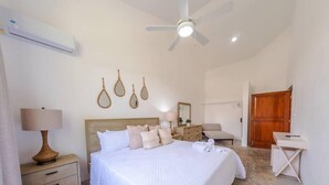 A bedroom with a bed, bedside table, lamp, wall decor, and a ceiling fan.
