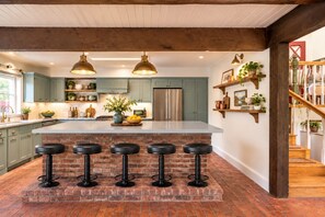 A kitchen with a central island, bar stools, and pendant lighting.
