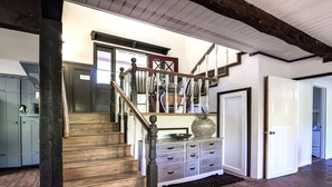 A staircase with wooden steps and a dark balustrade, leading to a landing with a white door and a white cabinet with drawers. - Riverside Home With a Rustic Charm (Washougal)