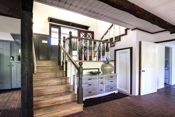 Un escalier avec des marches en bois et une balustrade sombre, menant à un palier avec une porte blanche et un meuble blanc doté de tiroirs.