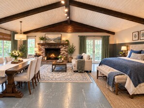 A spacious room with a fireplace, a dining area, and a large bed.