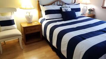 A neatly arranged bedroom with a large bed, two bedside tables, a chair, and lamps.