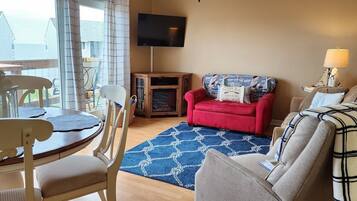A living room with a red sofa, a blue patterned rug, a wooden cabinet, and a television mounted on the wall.