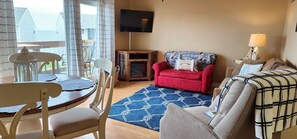 A living room with a red sofa, a blue patterned rug, a wooden cabinet, and a television mounted on the wall.