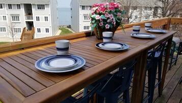 A wooden deck with a table set for four, overlooking a residential area.