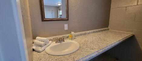 A bathroom with a granite countertop, a white sink, and a mirror.