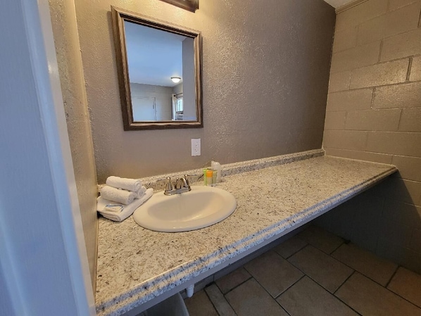 A bathroom with a granite countertop, a white sink, and a mirror.