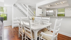 A modern kitchen with white cabinetry, a stainless steel refrigerator, and a dining area with a white table and chairs. - Lakefront Retreat at Smith Mountain Lake. Covered Boat Slip + Kayaks (Moneta)