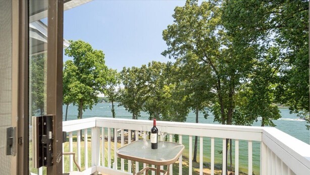 A balcony with a glass table, a bottle of wine, and a chair. - Lakefront Retreat at Smith Mountain Lake. Covered Boat Slip + Kayaks (Moneta)