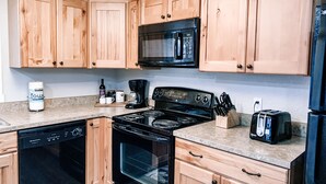 Una cocina con armarios de madera, un microondas negro, una estufa y un lavavajillas.