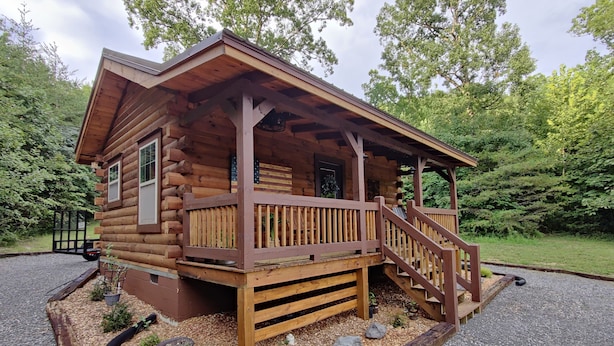 A wooden cabin with a porch, surrounded by gravel and small plants. - Bennett Lake Tiny Cabin  (Whitwell)