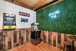 Une pièce avec un plancher en bois, un néon affichant le message «Seules les bonnes ondes sont les bienvenues» et des bornes d’arcade.