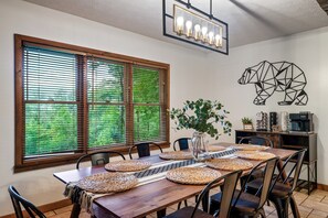 Un coin repas avec une table en bois, agrémentée de sets de table, de chaises et d’un vase avec une plante.