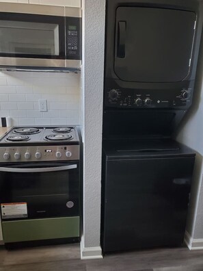 Une cuisine équipée d’une cuisinière à gaz, d’un four, d’un four à micro-ondes et d’un lave-vaisselle noir.