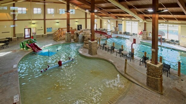 An indoor swimming pool with multiple lanes, a slide, and a waterfall feature. - Wisconsin Dells | Pool & Waterpark Access | 3BR Townhome  Sleeps 8 (Wisonsin Dells)