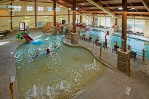 Ein Hallenbad mit mehreren Bahnen, einer Rutsche und einem Wasserfall.