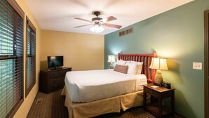 A hotel room with a bed, a television on a dresser, a ceiling fan, and a nightstand with a lamp. - Wisconsin Dells | Pool & Waterpark Access | 3BR Townhome  Sleeps 8 (Wisonsin Dells)