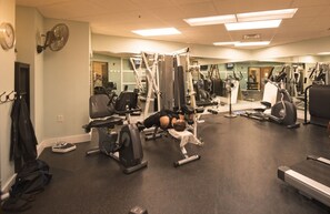 Une salle de sport équipée de divers appareils d’exercice, notamment des tapis de course, des vélos d’appartement et des appareils de musculation.