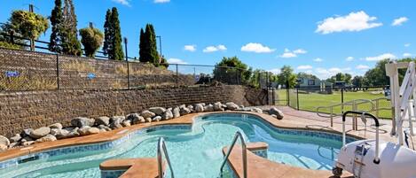 A swimming pool with a 3-foot depth marker, surrounded by a brick wall, a grassy area, and trees.