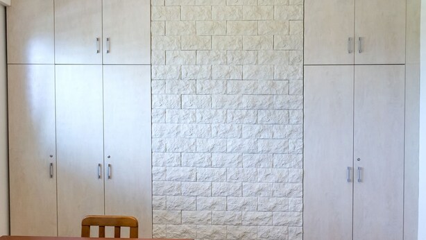 A room with a wooden table, a chair, and a wall with a textured pattern. - C006 - Camerano, new three-room apartment with garden (Camerano)