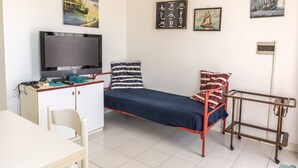 Una stanza modesta con un letto, una scrivania, una televisione e opere d'arte alle pareti.