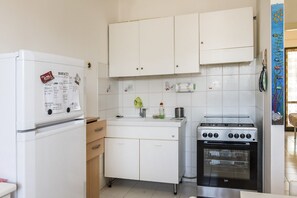 A compact kitchen with white cabinets, a built-in oven, and a refrigerator. - M323 - Marcelli, delightful three-room apartment with garden (Marcelli)