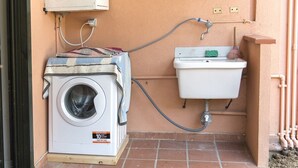 Un angolo lavanderia funzionale con lavatrice, lavandino e tubo.