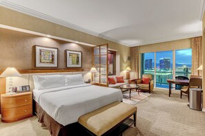 Une chambre d’hôtel avec un grand lit, deux tables de chevet, un bureau, une chaise et une vue sur le paysage urbain.