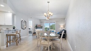 A spacious kitchen with a dining area, white cabinetry, and a chandelier.