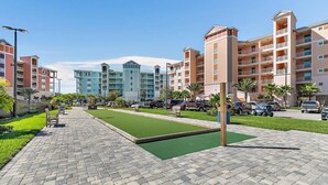 A courtyard with a green lawn, paved walkway, and multi-story buildings with balconies.