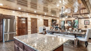 A spacious kitchen with granite countertops, wooden cabinets, and a stainless steel refrigerator. - Giant Luxury 10BR Cabin Huge Outdoor Area, Pool (Sevierville)