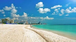 Une plage avec un ciel dégagé et, en arrière-plan, la silhouette d’une ville.