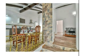 Amplia sala de estar con mesa de comedor, sillas y una escalera que lleva a otra habitación.