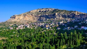 A town with buildings on a hillside, surrounded by dense green trees. - Konerkon Otel Plaza (Ermenek)