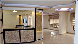 A reception area with a glass partition, a flat-screen TV, and a decorative wall panel. - Konerkon Otel Plaza (Ermenek)