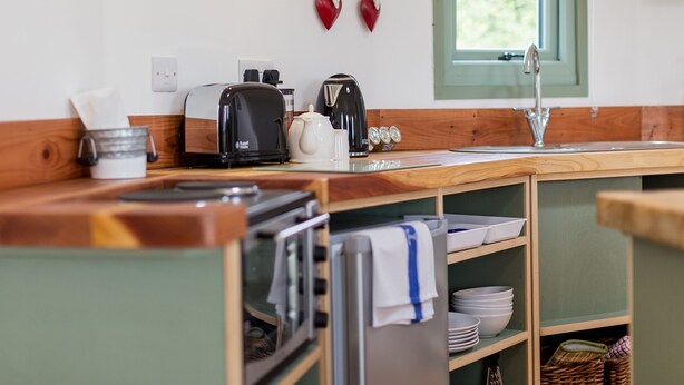 Une cuisine avec un plan de travail en bois, un grille-pain, une bouilloire et un évier.