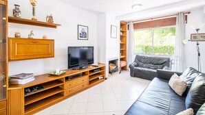 Un salon équipé d’un téléviseur, d’un meuble de rangement en bois, d’un canapé en cuir et d’une grande fenêtre.