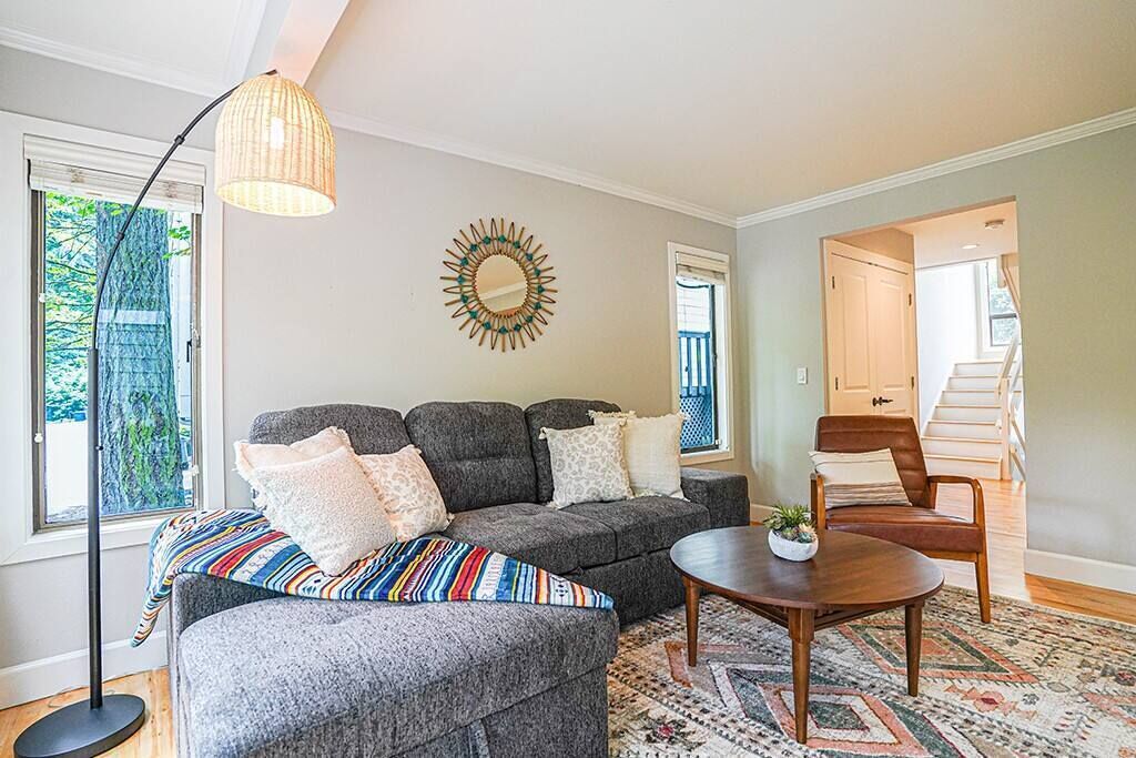 A living room with a gray sectional sofa, a round coffee table, and a patterned rug.