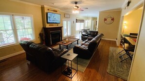 A living room with a fireplace, leather sofas, a coffee table, and a television. - Beautiful Lake Lanier Home, 2 story dock, Paddle Boards, & Pedle Boat (Dawsonville)