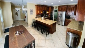 A modern kitchen with wooden cabinets, a central island with stools, stainless steel appliances, and pendant lighting. - Beautiful Lake Lanier Home, 2 story dock, Paddle Boards, & Pedle Boat (Dawsonville)