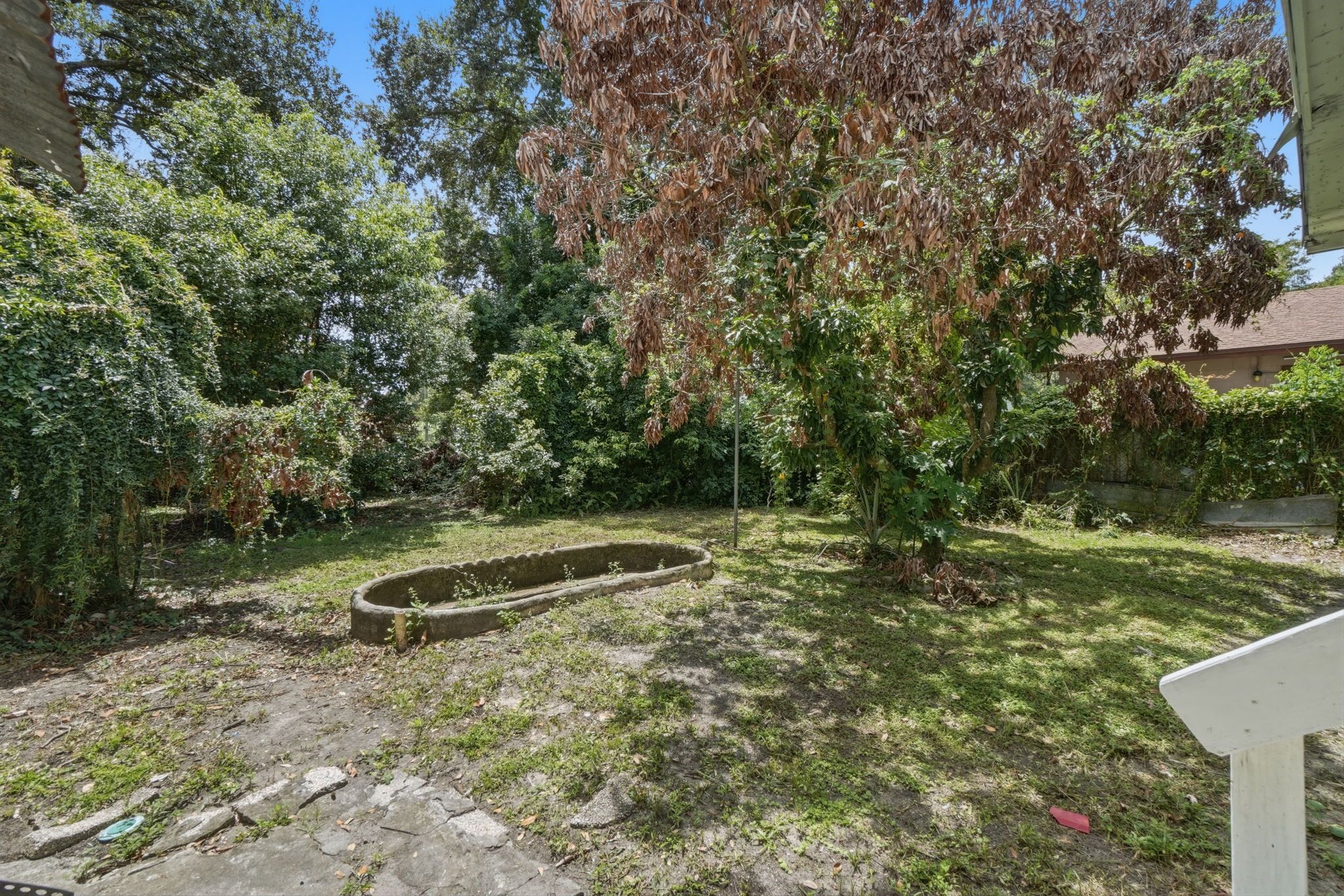 Un jardin agrémenté d’une structure circulaire en pierre, entouré de divers arbres et arbustes.