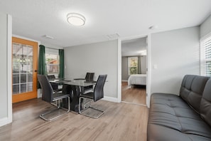 Une pièce comprenant une table à manger, des chaises, un canapé et un lit.