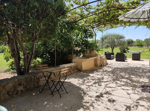 An outdoor patio area with stone benches, a hammock, and a pergola providing shade. - Provençal farmhouse-Jacuzzi-garden 5000m2-Children's'area -Ping Pong-Pétanque-BBQ-quiet (Pernes-les-Fontaines)