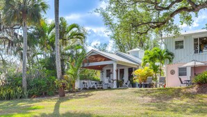 A house with a covered patio, outdoor seating, and lush greenery. - Waterfront Stuart Oasis w/ Hot Tub & Dock! (Stuart)